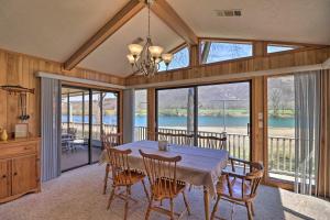 a dining room with a table and chairs and windows at Scenic Riverview Getaway with Screened Porch! in Norfork