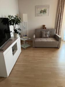 a living room with a couch and a television at BacherlHouse - Apt Miglbach in Schörfling