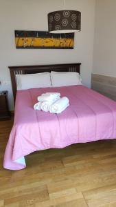 Una cama rosa con toallas encima. en Residencial Cabodeiro, en A Illa de Arousa