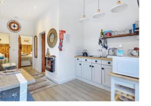 a kitchen with white cabinets and a living room at Minimoore Lodge. Perfect for walkers, cyclists and surfers. in Scorrier