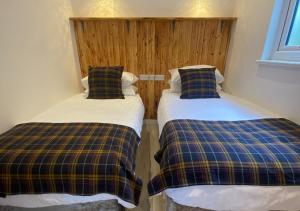 dos camas sentadas una al lado de la otra en una habitación en Minimoore Lodge. Perfect for walkers, cyclists and surfers., en Scorrier
