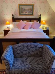 a bed with pink pillows and a chair in a room at The Grange in North Cadbury