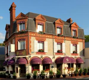 a large brick building with flowering plants in front of it at Chez Madame Cailleau in Houlgate