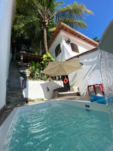 a swimming pool in front of a house at Casa Vila Mar - Inn Prainha in Arraial do Cabo