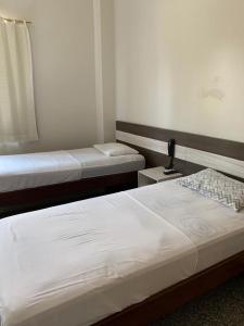 1 dormitorio con 2 camas y una lámpara en una mesa en HOTEL QUALITY, en Parauapebas