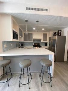 a kitchen with two bar stools and a counter at Great Beach Swiming Pools Tennis Courts Condo in La Paloma Rosarito Beach in Rosarito