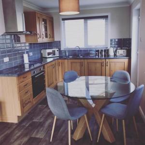 a kitchen with a glass table and blue chairs at Wick Holiday Home - NC500 Route in Wick