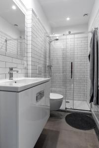 La salle de bains blanche est pourvue d'un lavabo et de toilettes. dans l'établissement Noclegi LIW APARTMENTS Hotel Apartamenty, à Liw