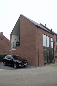 une voiture noire garée devant un bâtiment en briques dans l'établissement Aan Wal, à Rekem