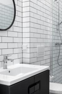 La salle de bains blanche est pourvue d'un lavabo et d'un miroir. dans l'établissement Noclegi LIW APARTMENTS Hotel Apartamenty, à Liw