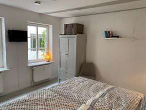 a bedroom with a bed and a cabinet and a window at Hafenkoje Husum in Husum