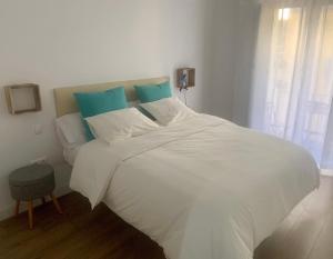 una camera da letto con un letto bianco con cuscini blu di PUERTA DE CACERES Apartamento 4 a Cáceres