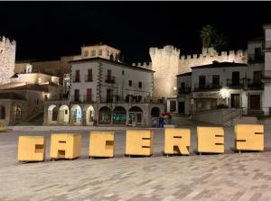 un grande cartello di fronte a un castello di notte di PUERTA DE CACERES Apartamento 4 a Cáceres