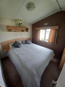 een groot wit bed in een slaapkamer met een raam bij Jacqueline's holiday homes seawick clacton on sea in Saint Osyth