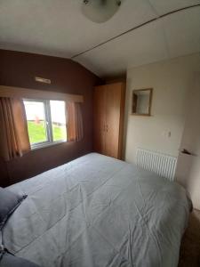 1 cama grande en un dormitorio con ventana en Jacqueline's holiday homes seawick clacton on sea, en Saint Osyth