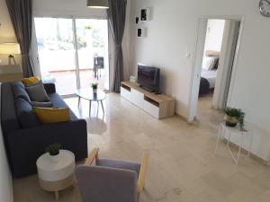 een woonkamer met een bank en een tv bij Blue Coast Semeli by the Sea in Nea Paphos
