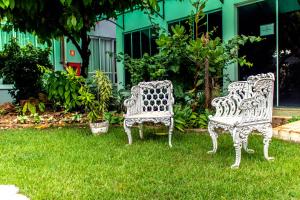 two white chairs sitting in the grass in a yard at Delcas Hotel in Cuiabá