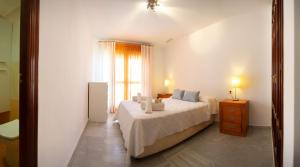 a white bedroom with a bed and a window at Brasil Playa Ha Apartment in Cádiz