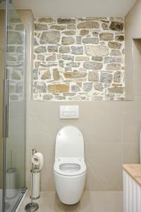a bathroom with a white toilet and a stone wall at BAY BREEZE Holiday house in Piran in Piran