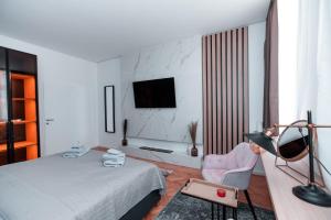 Petit luxe Apartment في فيينا: غرفة نوم بسرير وكرسي وتلفزيون
