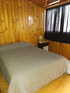 1 dormitorio con 1 cama en una habitación con paredes de madera en Departamentos Muñoz en Río Grande