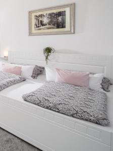 een wit bed met roze en grijze kussens bij Apartmán U Pramene in Františkovy Lázně