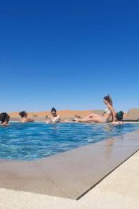 - un groupe de personnes se posant dans une piscine dans l'établissement Riad Caravasar, à Merzouga