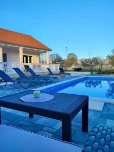 a pool with a table and chairs next to a house at Mediterranean Olive WaterfallsKRKA-Croatia in Gulin