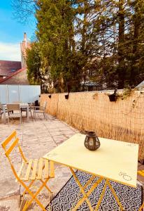 une table et des chaises jaunes sur une terrasse dans l'établissement Appartement 2 chambres avec terrasse vue sur jardin arboré, à Pontarlier