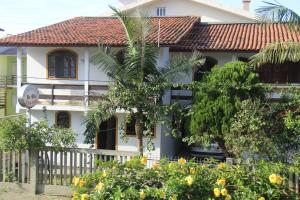 una casa blanca con una palmera delante de ella en Niko Residencial, en Florianópolis
