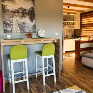 a kitchen with a bar with two green chairs at Apartment Little Paradise in Visoko