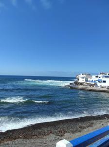 a blue bench sitting on a beach next to the ocean at Laylas Beach Art House in Cotillo