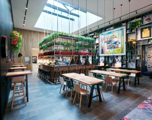 a restaurant with wooden tables and chairs and plants at citizenM Los Angeles Downtown in Los Angeles