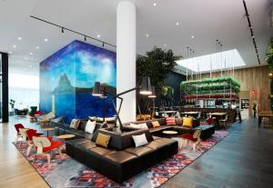 a lobby with couches and chairs and a mural at citizenM Los Angeles Downtown in Los Angeles