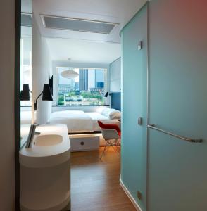 ein Schlafzimmer mit einem Bett, einem Schreibtisch und einem Fenster in der Unterkunft citizenM Los Angeles Downtown in Los Angeles