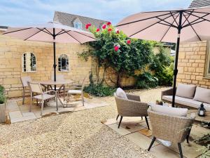 a patio with a table and chairs and umbrellas at Lavender Lodge Bourton in Bourton on the Water