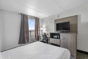 a hotel room with a bed and a flat screen tv at Emerald Hotel & Suites Calgary Airport in Calgary