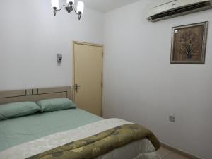 a bedroom with a bed in a white room at Furnished Apartment in Sharjah