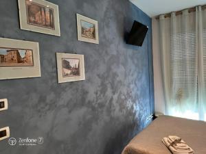 a bedroom with a gray wall with pictures on it at B&B San Vitale in Bologna