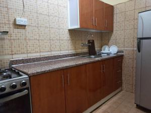 a kitchen with wooden cabinets and a sink and a refrigerator at Furnished Apartment in Sharjah