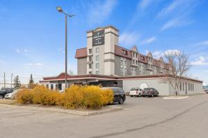 un gran edificio con coches estacionados en un estacionamiento en Emerald Hotel & Suites Calgary Airport en Calgary