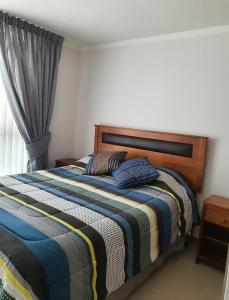 1 dormitorio con 1 cama con manta a rayas y ventana en Marina Casino Playa en Coquimbo