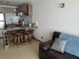 a living room with a couch and a kitchen at Marina Casino Playa in Coquimbo