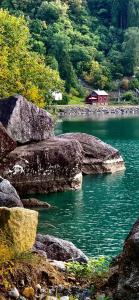 a river with a red house in the middle at Vasstun Panorama in Odda