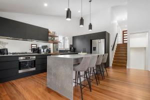 a kitchen with black cabinets and a bar with stools at 24 Hibiscus Crescent Port Macquarie in Port Macquarie