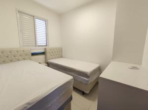 a white room with two beds and a window at Home Resort - Apto JPII48B Ubatuba in Ubatuba
