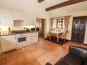 a kitchen with white cabinets and a table at Parlour Barn in Charlton