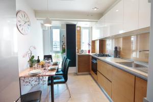 a kitchen with a table with chairs and a clock on the wall at Gold Class Apartments AMS in Cluj-Napoca
