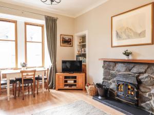 a living room with a fireplace and a dining room table at Aultmore in Kingussie
