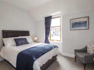 a bedroom with a bed and a window and a chair at Aultmore in Kingussie